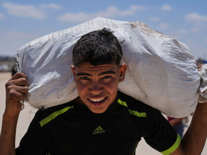 A Palestinian youth carries food and humanitarian aid delivered by the U.S.-backed Gaza Hu